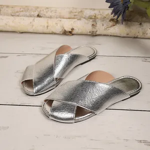 Silver metallic snakeskin texture flat mule slippers for women on wooden background.