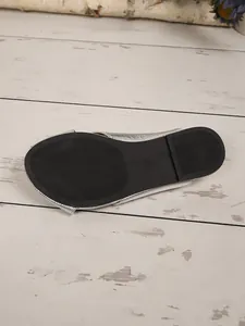 Close-up of black anti-slip sole for silver flat mule slippers in size 37.