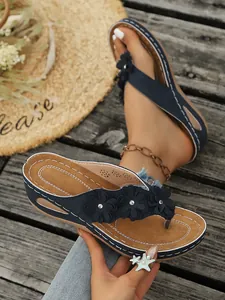 Gedetailleerd overzicht van donkerblauwe sleehak slippers met bloemendecoraties.
