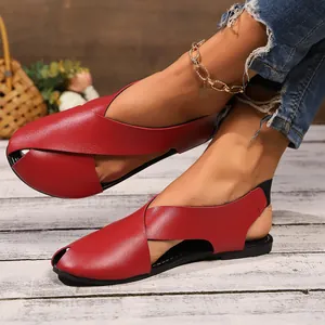 Detailansicht roter flacher Sandalen mit Kreuzriemen aus weichem Leder am Fuß