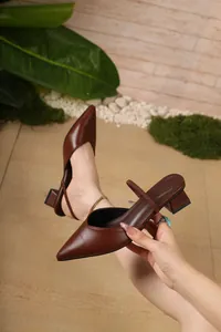 Primo piano dettagliato delle eleganti sabot marroni a punta con tacco basso largo