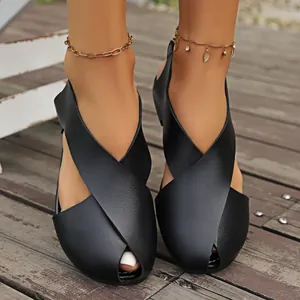 Detailansicht schwarzer flacher Sandalen mit Kreuzriemen und Peep-Toe auf Holzdeck
