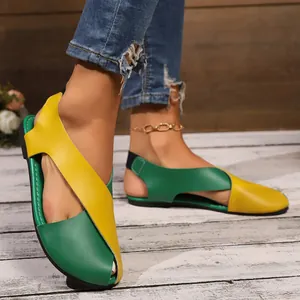 Detailansicht der gelb-grünen Kreuzriemen-Flachsandalen für Damen am Fuß des Models