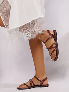 Detailed side view of burgundy flat gladiator sandals with cross straps and toe loop