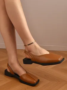 Dettaglio ravvicinato di eleganti sandali marroni a punta quadrata indossati da una modella