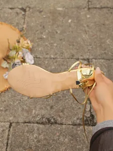Nahaufnahme der Sohle einer goldenen High-Heel-Sandale mit schmalem Absatz.