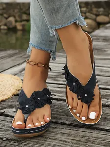 Detailweergave van dames flip-flops met sleehak, bloemapplicaties en strasstenen