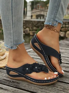 Detail van marineblauwe sleehak slippers met bloemen en witte stiksels