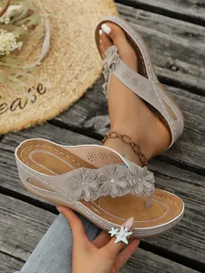 Zomerse wedge slippers voor dames met elegante bloemdecoratie op houten achtergrond