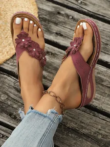 Close-up van bordeauxrode platform slippers met bloemaccenten en strass-steentjes
