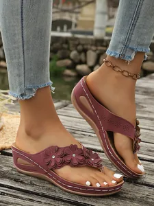 Detailopname van bordeauxrode sleehak-slippers met 3D-bloemen en glinsterende steen