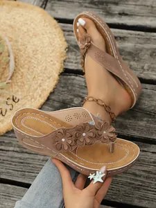 Detail van stijlvolle bruine sleehaksandalen met 3D bloemen en luxe glanzende stras.