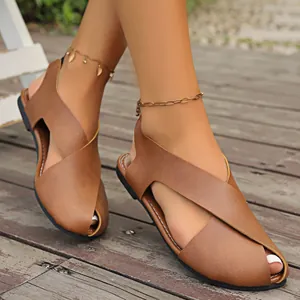 Braune Peep-Toe-Sandalen mit Kreuzriemen, präsentiert auf einem Holzdeck.