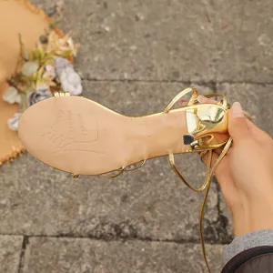 Detailansicht des goldenen Metallic-Finishs und der Sohle von sexy Schnürsandalen mit Absatz