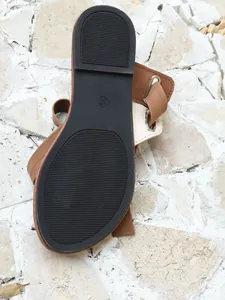 Nahaufnahme der strapazierfähigen schwarzen Gummisohle dieser braunen Sandalen.
