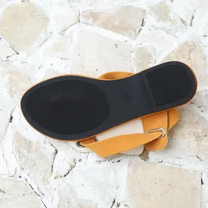 Detailaufnahme der rutschfesten schwarzen Sohlentextur dieser gelben flachen Römersandalen