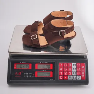 Detail view of brown suede sculptural heel sandals on a scale showing a weight of 0.415kg
