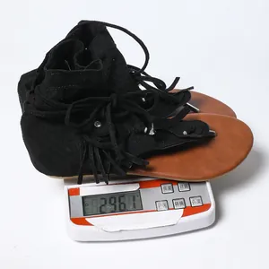 Báscula digital midiendo el peso de una sandalia romana con flecos negros, de 296,1 g.