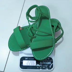 Green flat Roman sandals on a digital scale showing light weight of 228.6 grams