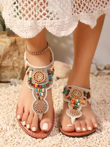 Detailweergave van bohemien-stijl platte teenslippers met kleurrijke kralen op de voeten