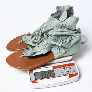 Primer plano de sandalias gladiador verde claro en una báscula con un peso de 302g.