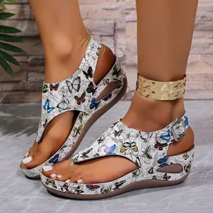 Primo piano dettagliato di sandali con zeppa da donna con stampe di farfalle colorate.