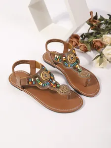 Detailweergave van bruine bohemien platte teenslippers met kleurrijke kralendecoratie.