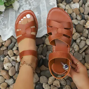 Stylish brown flat Roman sandals with soft cross straps for beach or casual wear