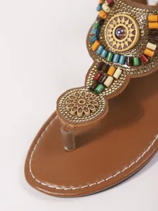 Detailweergave van Boheemse platte sandalen met kleurrijke kralen en bloemen.