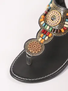 Detailweergave van kleurrijk kralenwerk op bohemian stijl platte teensandalen.