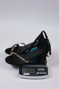 Detailed view of the black block heel sandals being weighed on a digital scale