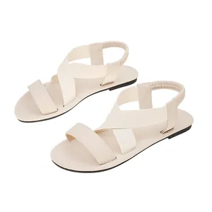 Detailed side view of beige women's flat beach sandals with comfortable elastic crossover straps