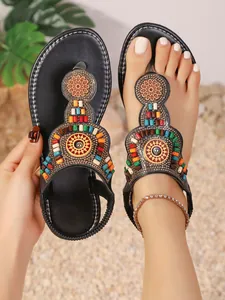 Detailopname van zwarte boheemse teenslippers met kleurrijke etnische kralenpatronen