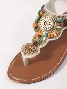 Detail van Boheemse platte teenslippers met kleurrijke kralen en gouden studs.