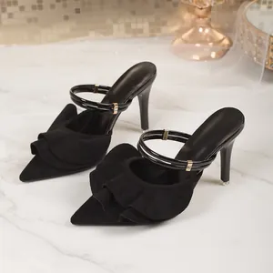 Elegant black suede stiletto heels with ruffle detail on white marble surface.
