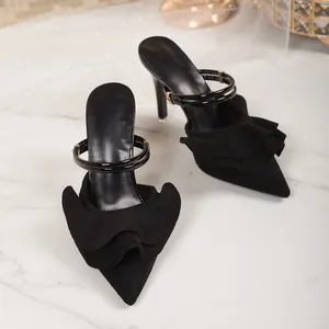 Elegant black pointed-toe stiletto heels with decorative ruffle detail on a marble surface.