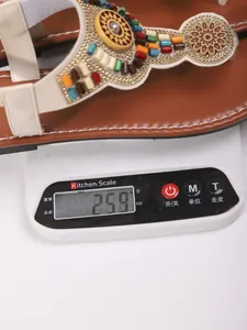 Detailopname van Bohemian platte teenslippers met een gewicht van 259g op een weegschaal