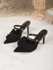 Close-up of elegant black pointed-toe stiletto mules with ruffle and double straps