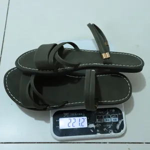 Detailed weight measurement of olive green flat Roman sandals on a digital scale showing 221.2g