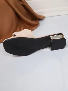 Detail van de beige sandaal met vierkante neus en glitteraccenten op de blokhak