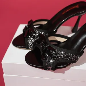 Close-up of black high heel sandals with sparkling glitter and elegant bow detail
