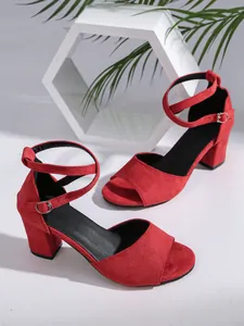 Detailed view of elegant red suede block heel sandals with an adjustable ankle strap.