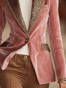 Dettaglio ravvicinato di blazer in velluto rosa con revers leopardati e bottoni dorati.