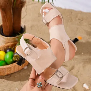 Detail view of beige suede sandals with unique sculptural kitten heel and square toe