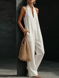 Detailed view of an elegant white sleeveless jumpsuit with a halter V-neck and side pockets.
