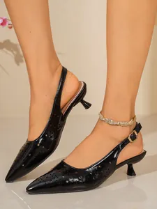 Vista dettagliata di scarpe kitten heel nere a punta con motivi traforati al laser.