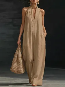 Model posing in an elegant khaki sleeveless halter jumpsuit with a wide-leg design