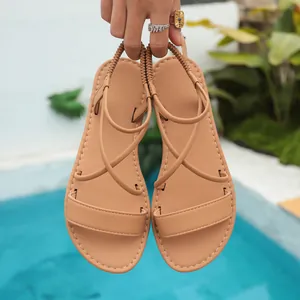 Close-up detail of tan flat Roman sandals with cross straps for summer beach wear