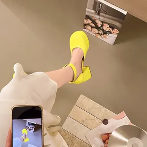 Close-up detail of vibrant yellow patent leather Mary Jane shoes with block heel and platform
