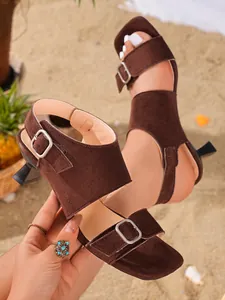 Detailed view of brown suede mule sandals with a sculptural heel and square toe